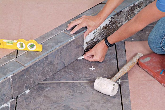 Place spacers and/or wedges under the riser tiles to adjust the grout joint at the top and form a caulk joint at the bottom.