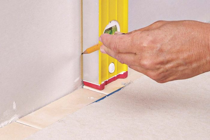 A plumb line drawn on the wall helps you line up the grout joints of the backsplash tiles with the tiles on the countertop.