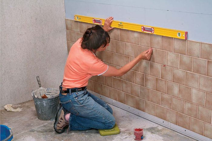 Continue tiling up the wall, checking every few rows with a level, and adjusting with spacers.