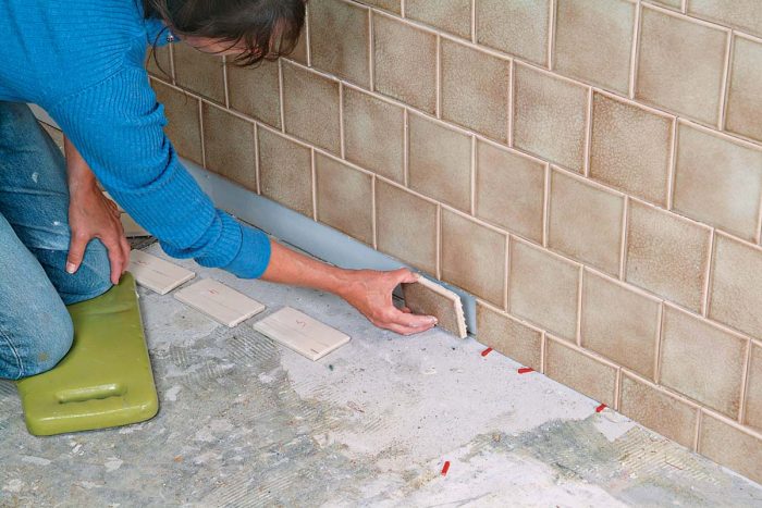 The next day, remove the ledger board, cut your bottom row of tiles, and back-butter and set them, adjusting with spacers.