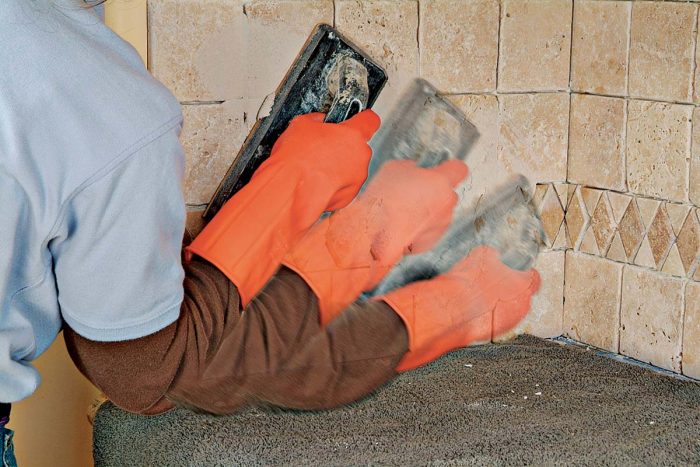 Spread grout firmly across the tile with the grout float. Use a low angle and fully pack the joints.