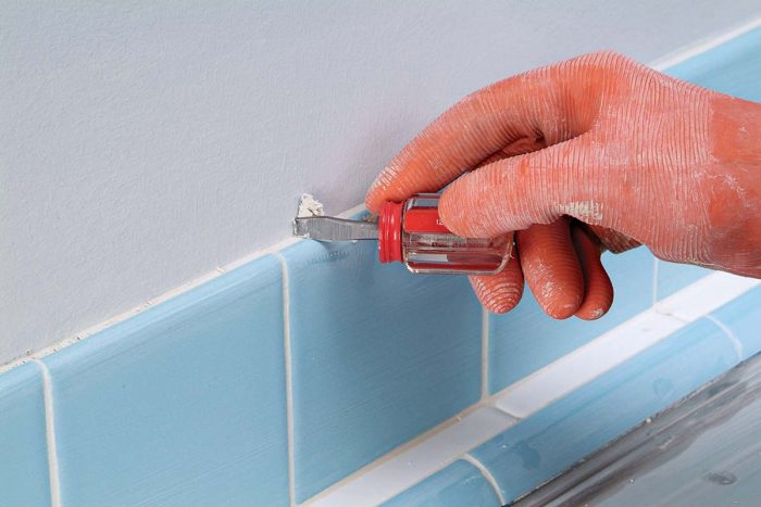 A screwdriver or chisel can be used to carve any excess grout from the top edge of tiles.