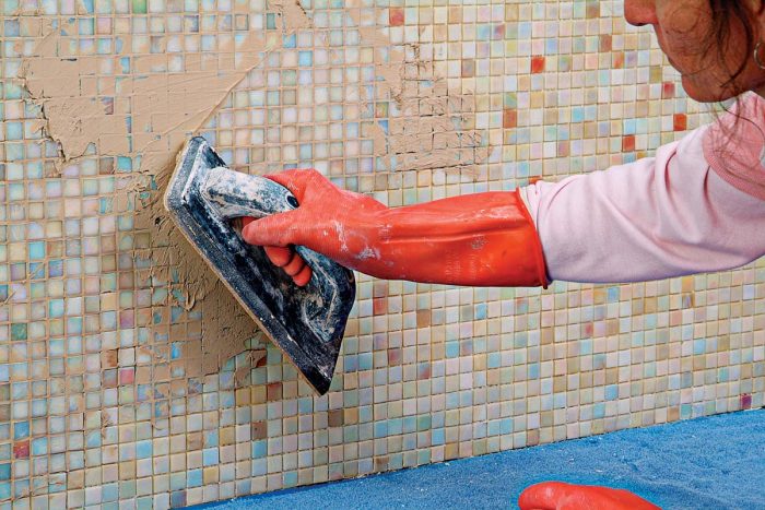 Apply the grout, then remove as much grout as possible from the face of the glass mosaics with a low-angled grout float.