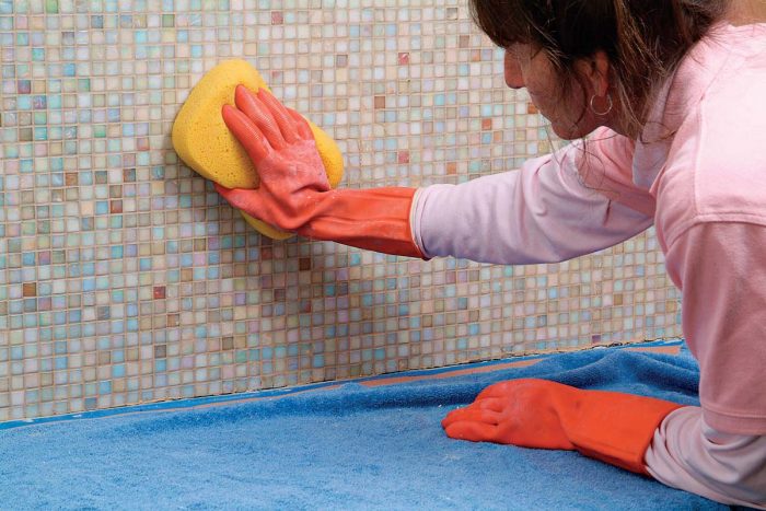 Wipe the excess grout from the glass tiles.