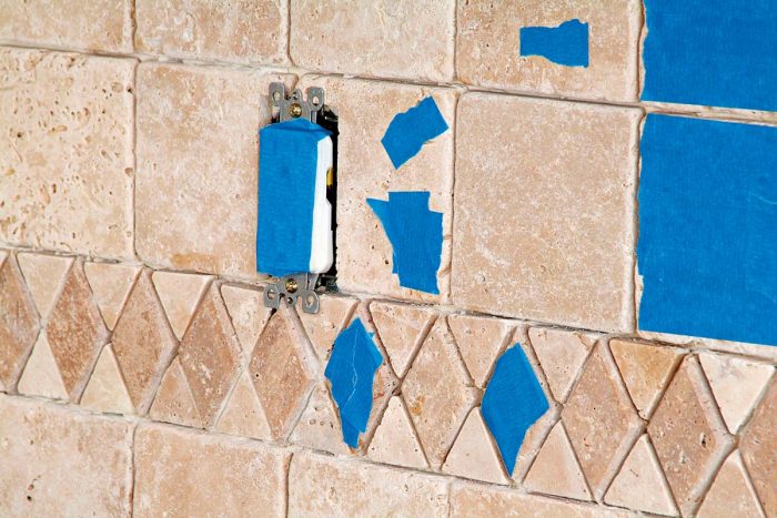 Use masking or blue tape on tiles to prevent grout from filling holes.