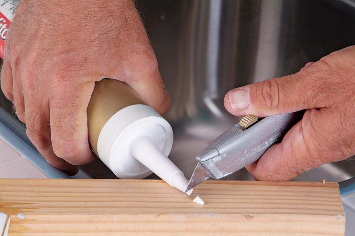 Slice off the tip of the caulk tube at an angle. Cut it near the top of the tube to ensure a small opening.