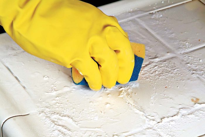 Scrub the grout and tile surface with the rough, nonmetallic side of the sponge.