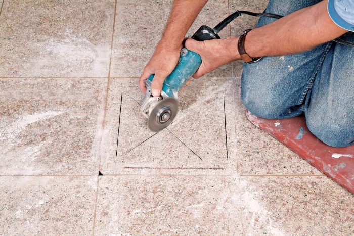 Use an angle grinder to cut an X before removing the rest of the tile.