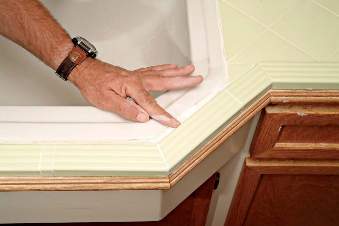 Use your finger to smooth caulk into the joint between the sink and edge tiles.