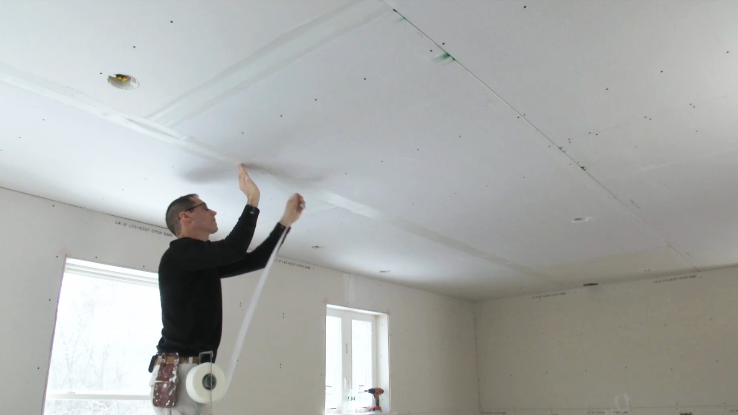 Myron taping drywall seams on the ceiling