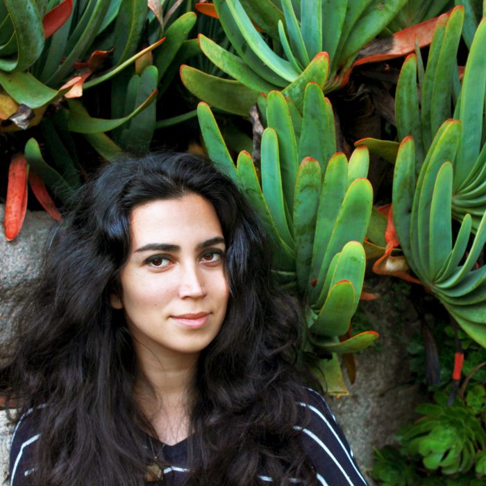 Headshot of Nahal Sohbati against a backdrop of green and red plants