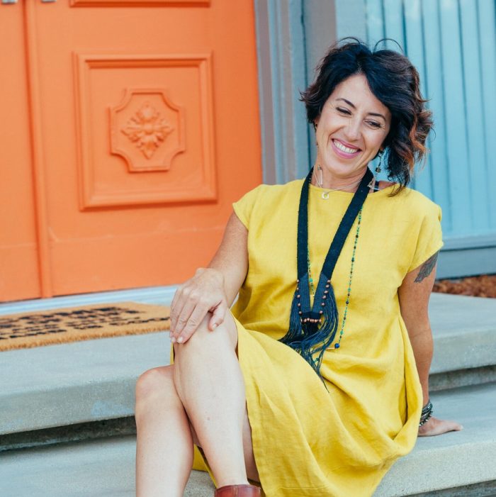 Jessica Viola in a yellow dress against a blue and teal door