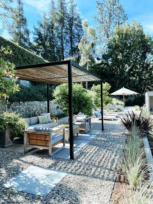 Outdoor landscape with shade structure against backdrop of trees