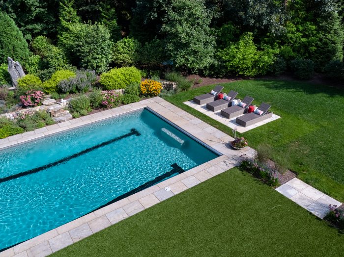 Bright blue pool surrounded by green lawn and trees