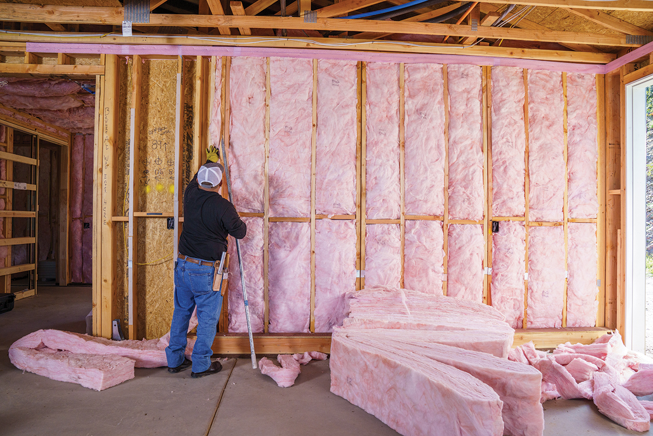 Man placing fiberglass batts between panels in a wall