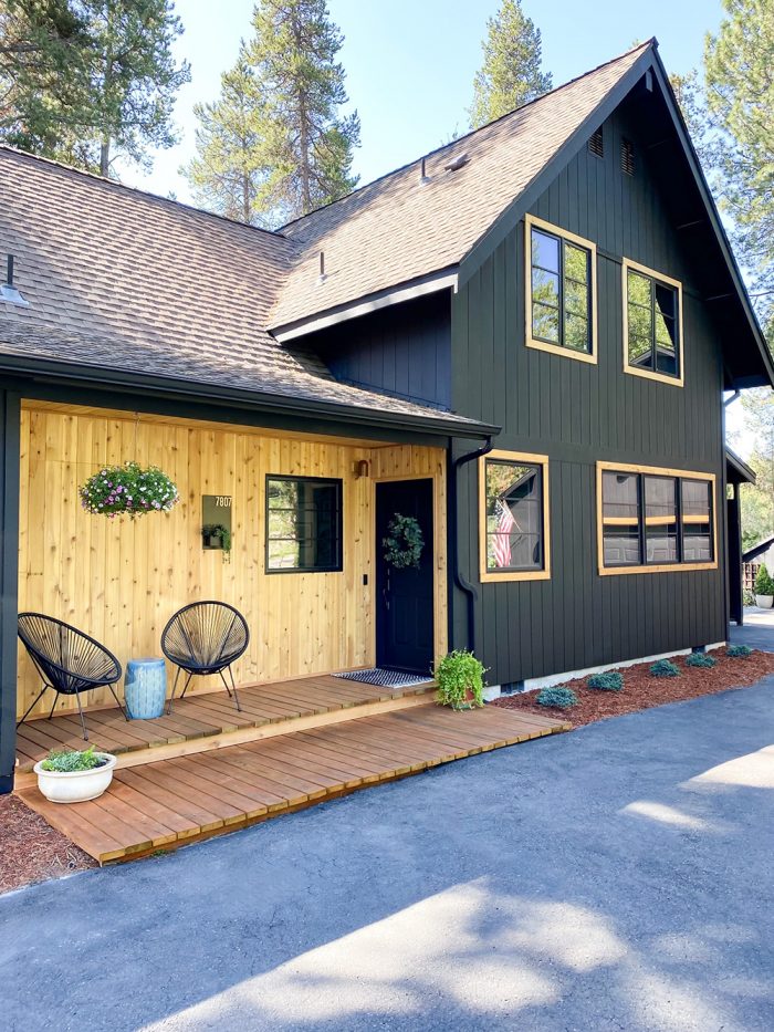 A house painted black with windows with wood trim