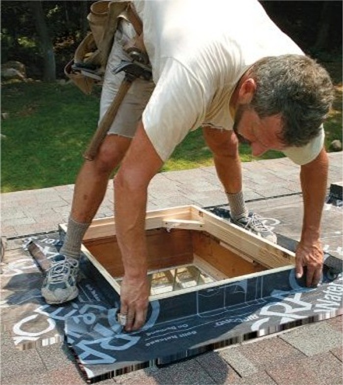 Skylight curb on a roof being wrapped with self-adhering membrane as backup protection to the primary roof flashing.