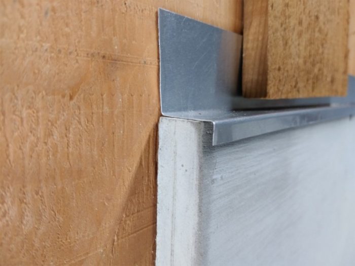 Uncoated aluminum drip cap flashing over trim. It's inadequate due to short wall leg, flat cap leg and short drip leg. And the cap flashing is only half the thickness required by building code.
