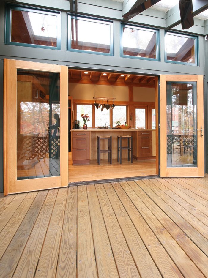 Large glass doors connecting an indoor dining area to an outside deck