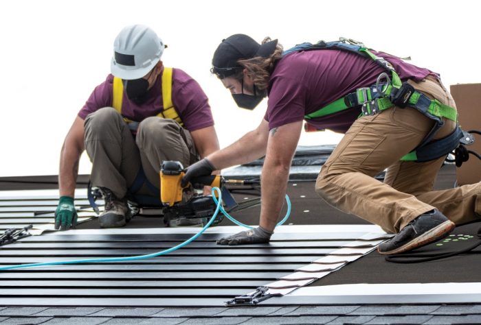 Workers nailing down GAF Energy's solar shingles.