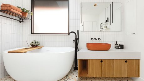 A white bathroom with a white tub and tangerine accents