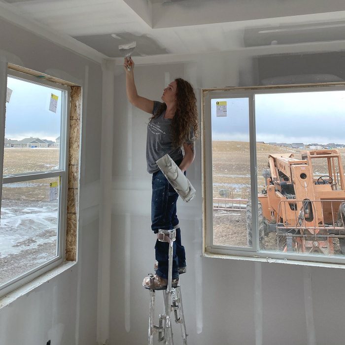 Lydia Crowder on drywall stilts working on a ceiling