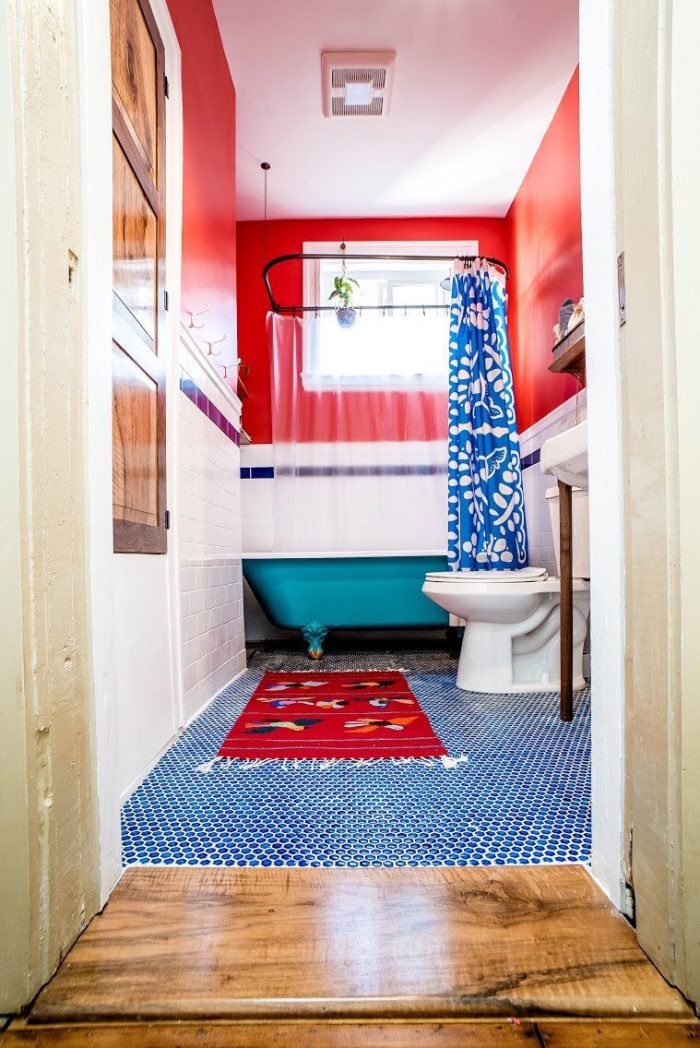 A remodeled bathroom with red walls and blue tiling