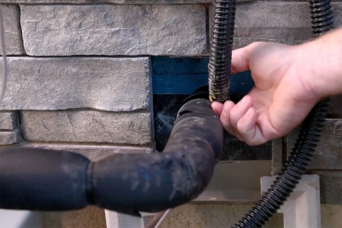 A close up photo of where the line set meets the condensor unit in the exterior of the wall