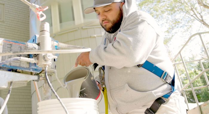 Painter pours paint into sprayer