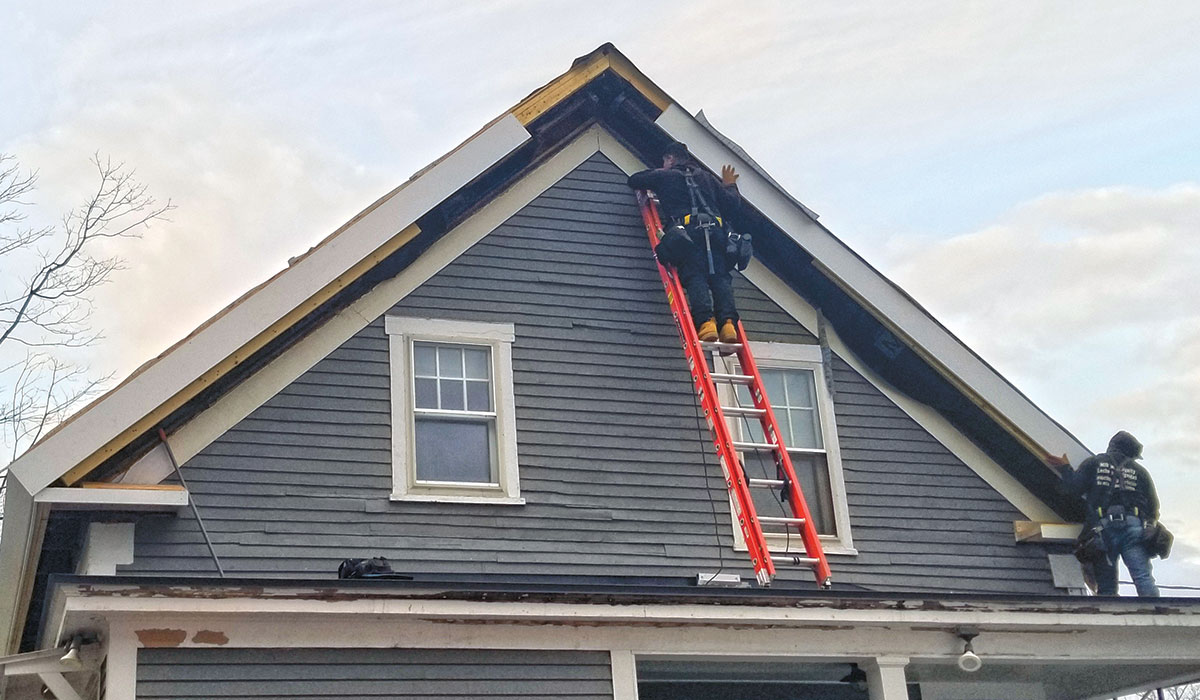 man on ladder working on roof gables