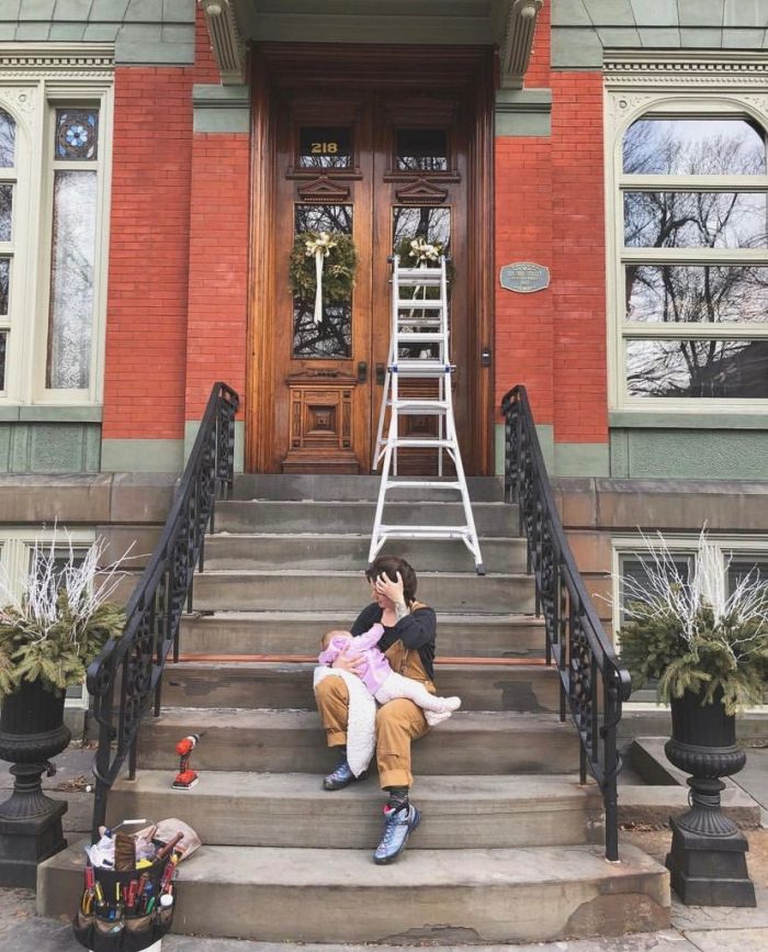 Sarah sits on a stoop with her child and surrounded by tools