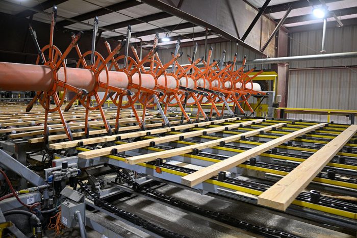 Orange wheels moving lumber through the conveyor