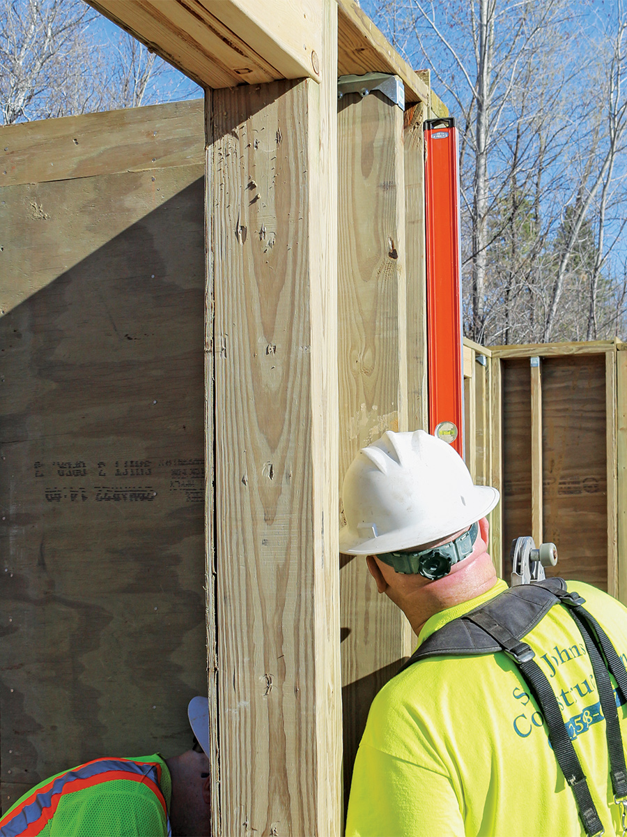 checking foundation wall panels are plumb with a 6-ft. level