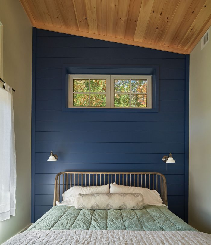 A bedroom with a blue wall and high wood ceilings
