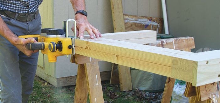 A closeup view of a cordless planer on a wood frame
