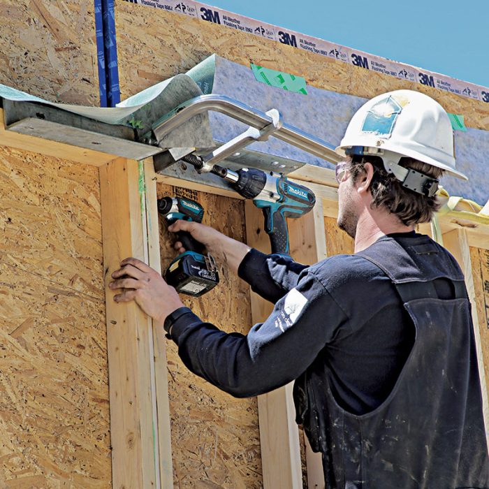 A worker connecting wall panels with a drill
