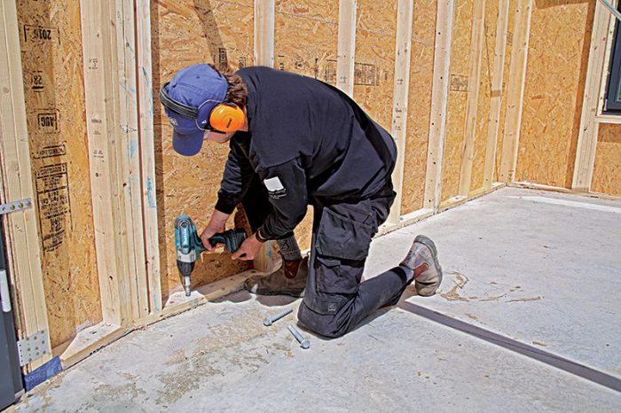 A person drilling anchor bolts through the panel into the foundation