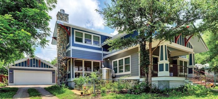 Photograph of a blue, two-story house built in the city.