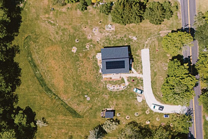 Aerial photo of a house in the suburbs surrounded by green grass.