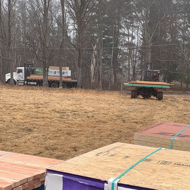 Photo of a forklift bringing wood to the building site.