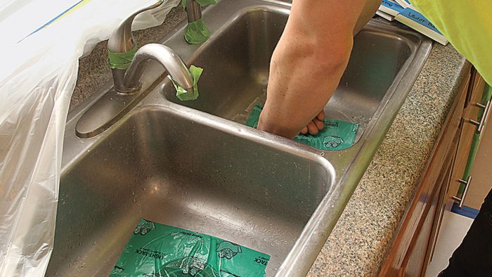 Photo of hands adding self-adhering film to plumbing fixtures.