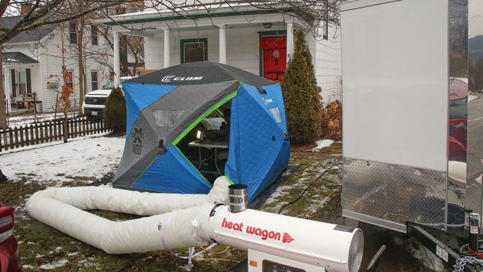 Photo of a blue and grey tent attached to a vehicle called "Heat Wagon."