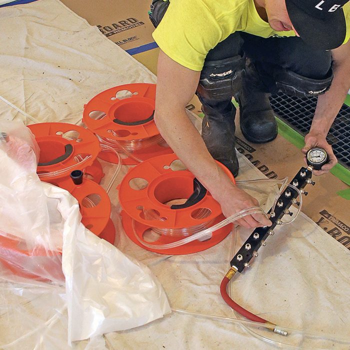 Photo of man in a neon yellow shirt connecting air supply tubes to the manifold.