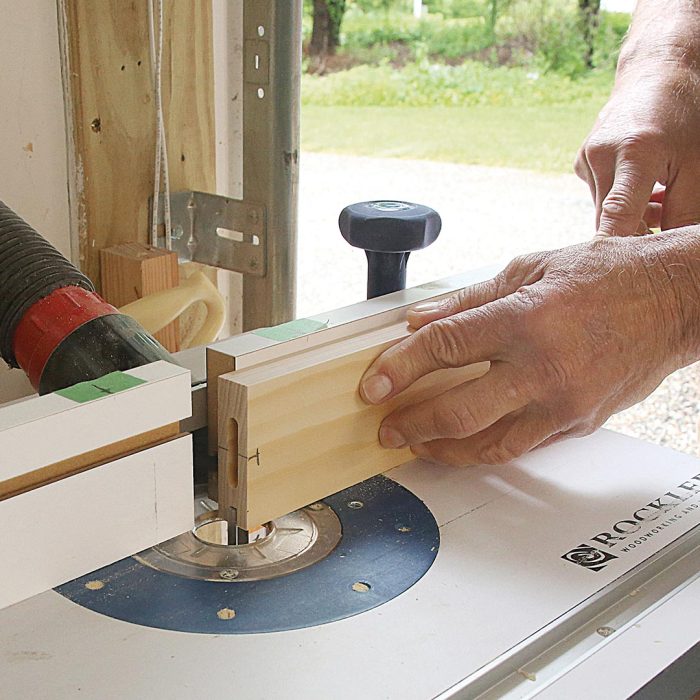 A photo of hands routing continuous grooves on the rails.