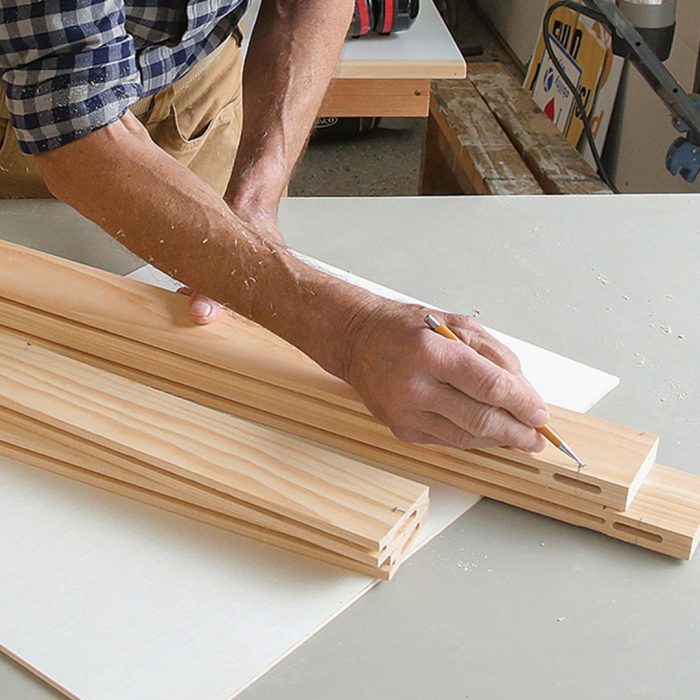 Photo of hands marking a piece of wood using a pencil.