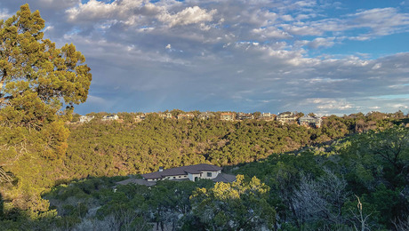 Photo of a landscape with lush greenery on the bottom and blue sky on the top.