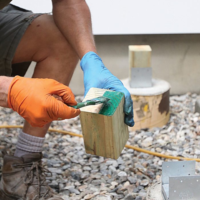 Man applying copper naphthenate to the cut ends of posts.